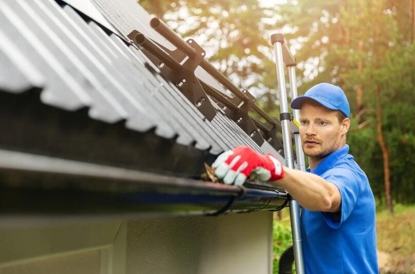 A professional cleaning a gutter