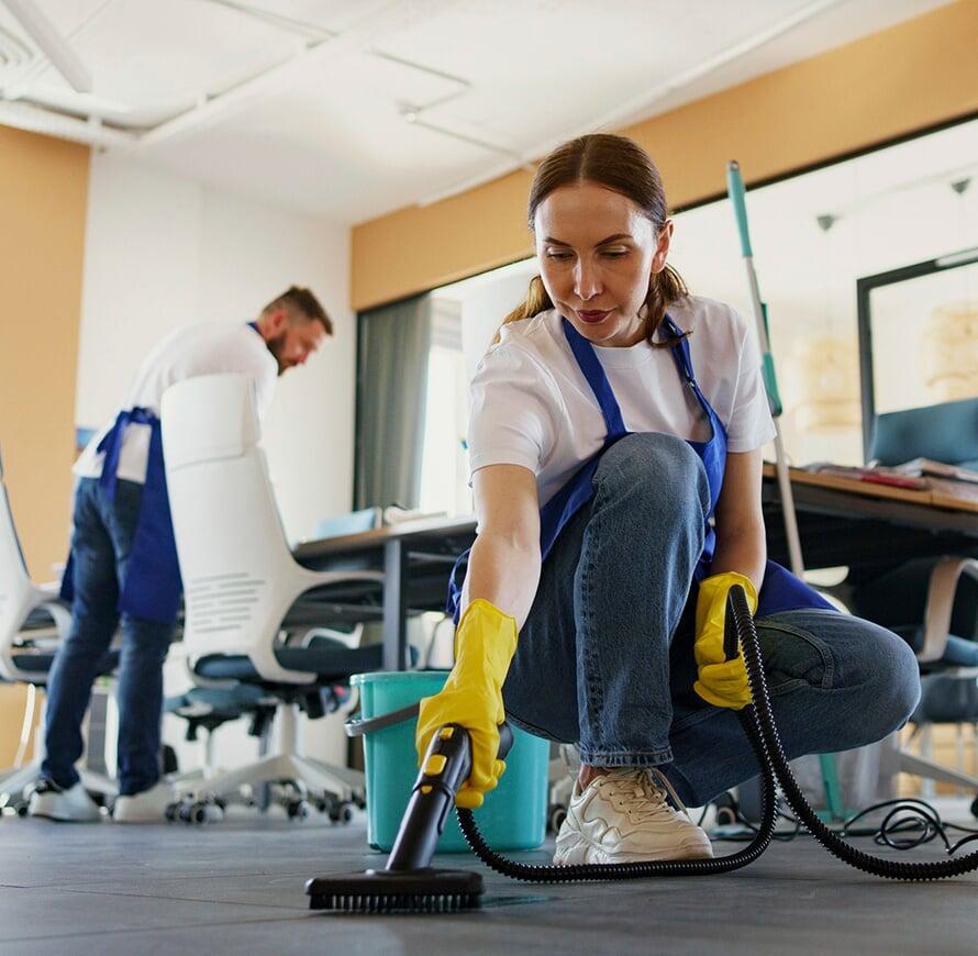 A team of cleaners vacuuming and wiping down an office space.